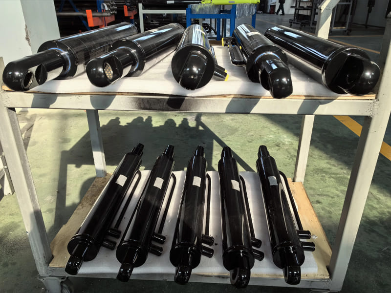 Batch finished black painted hydraulic cylinders placed on workshop storage rack